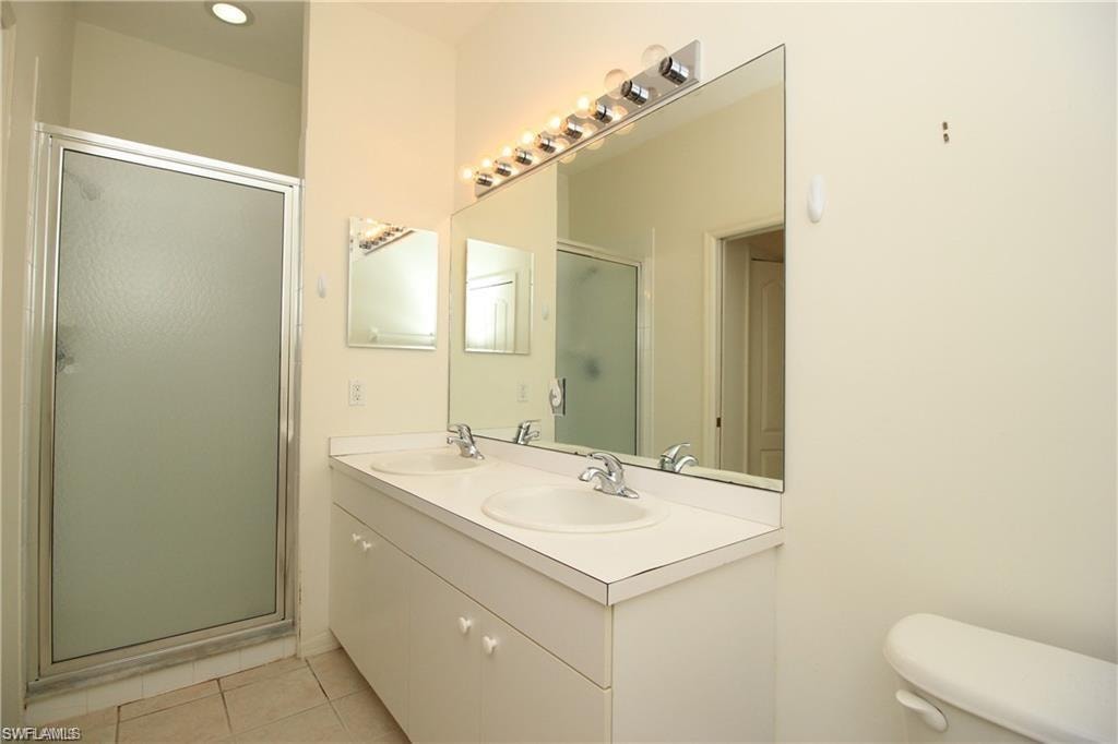 Bathroom with tile patterned flooring, vanity, toilet, and an enclosed shower