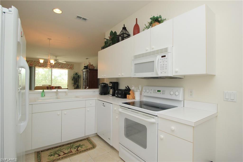 Kitchen with light tile patterned floors, white appliances, white cabinetry, sink, and ceiling fan