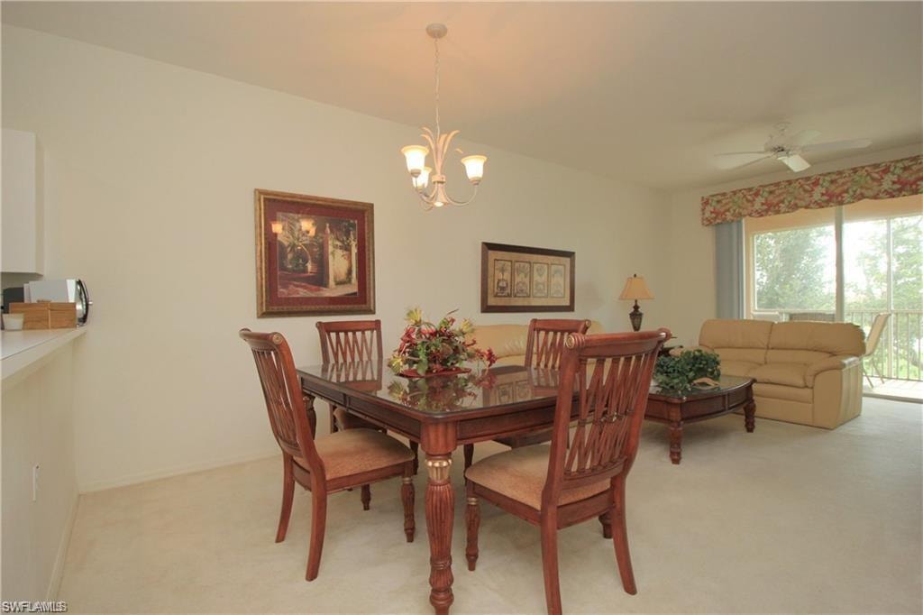 Carpeted dining area featuring ceiling fan with notable chandelier