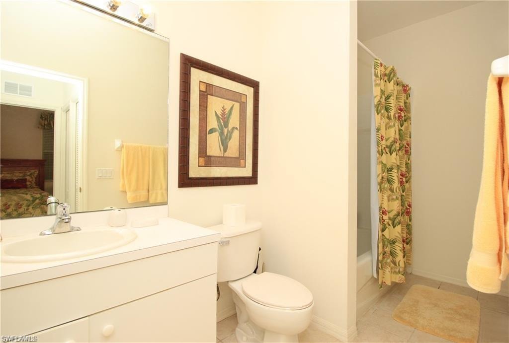 Full bathroom featuring shower / bathtub combination with curtain, tile patterned flooring, toilet, and vanity