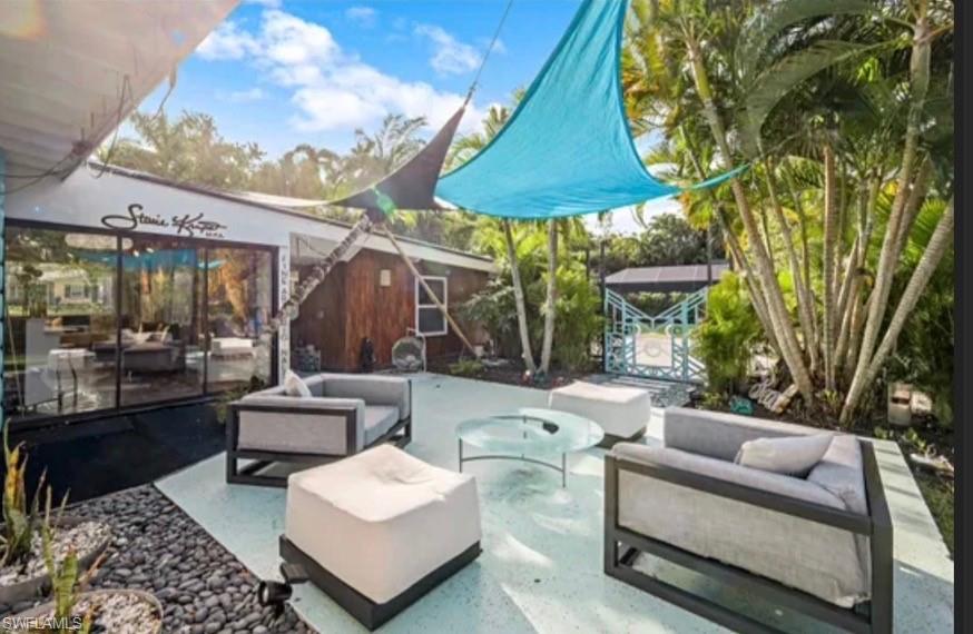 Outdoor patio with light-colored surfacing, surrounded by lush tropical landscaping and mature palm trees