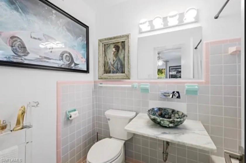 Bathroom featuring a vessel sink with a marble countertop, square tile walls, and a recessed medicine cabinet