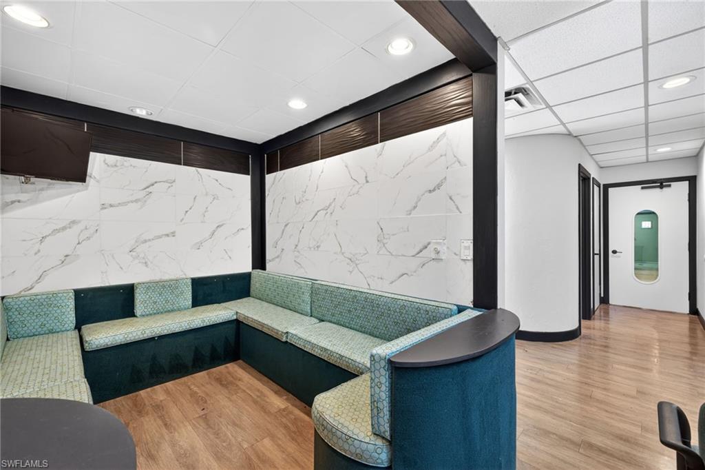 Lounge area featuring built-in L-shaped seating, large format wall tiles with veining, and wood-finish flooring