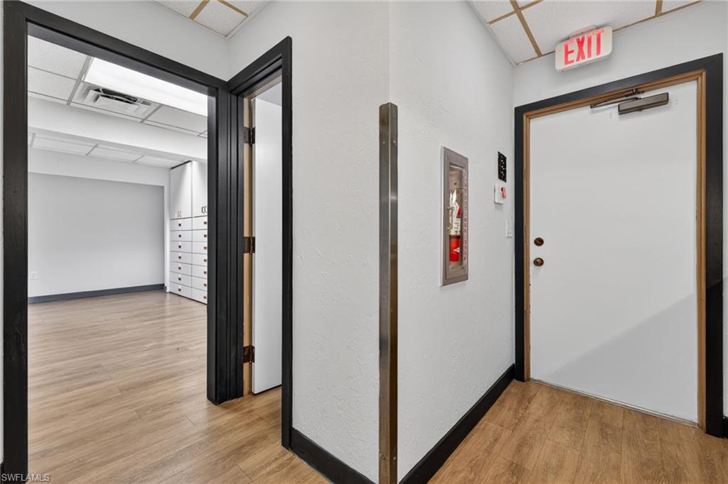 Hallway featuring wood-finish flooring, white walls, and black trim
