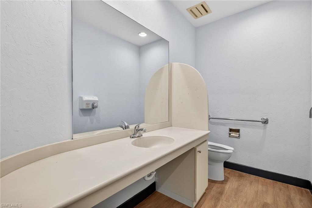 Bathroom with a single vanity, integrated sink, and wood-finish flooring