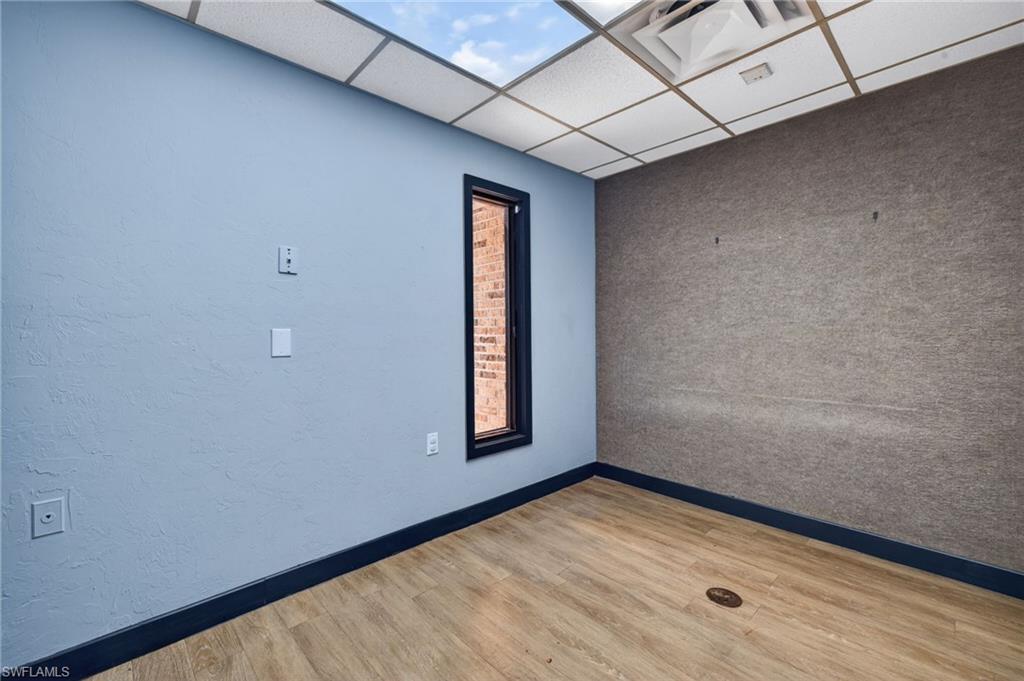 Room featuring wood-finish flooring, a ceiling with recessed lighting, and a window with dark trim