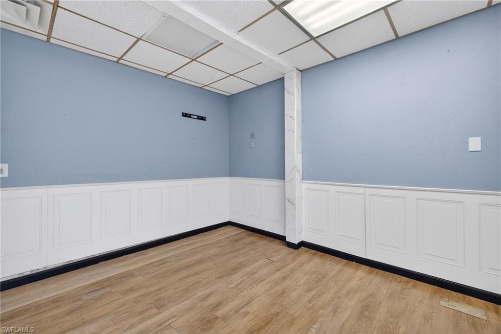 Spacious room featuring wood-finish flooring and wainscoting
