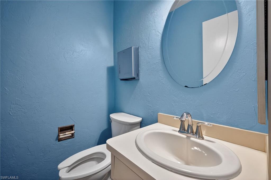 Bathroom featuring a white vanity with an integrated sink, chrome faucet, and oval mirror