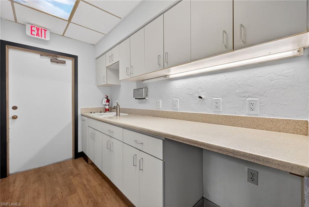 Functional utility area featuring extensive countertop space, integrated sink, and ample white cabinetry