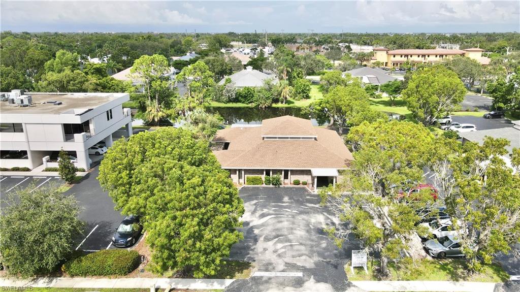 Commercial property featuring a brown shingle roof, ample parking, and a waterside setting