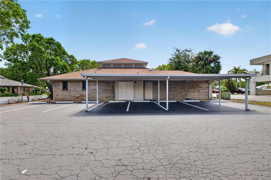 Brick exterior featuring a hip roof and a covered carport
