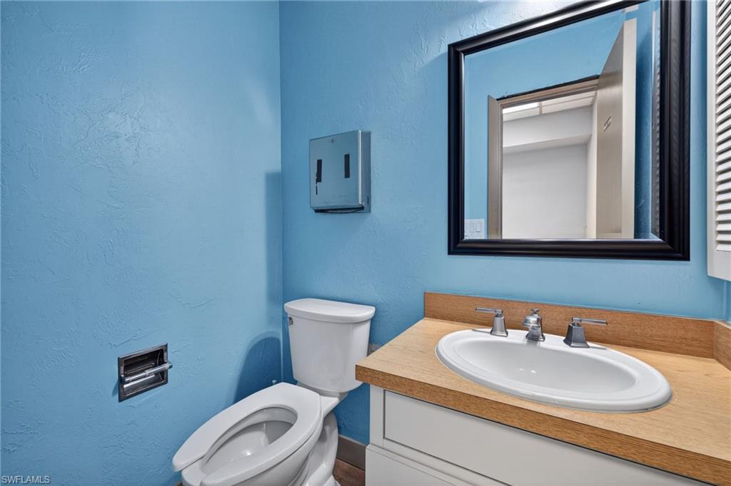 Full bathroom featuring a single white porcelain vanity sink with chrome fixtures, a wood-finish countertop, and a framed mirror