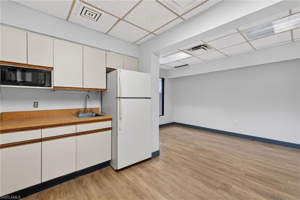 Compact kitchen area featuring wood-finish countertops, white cabinetry with wood trim, a stainless steel sink, and a built-in microwave