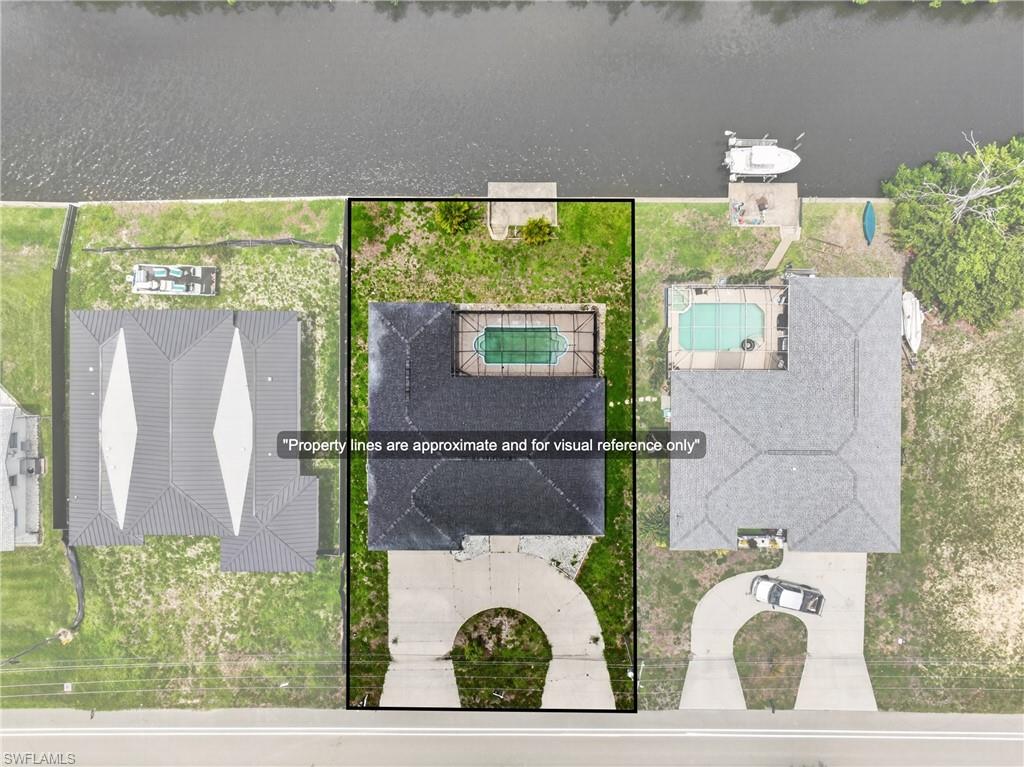 Waterfront property featuring a private boat dock, in-ground swimming pool, and a circular driveway