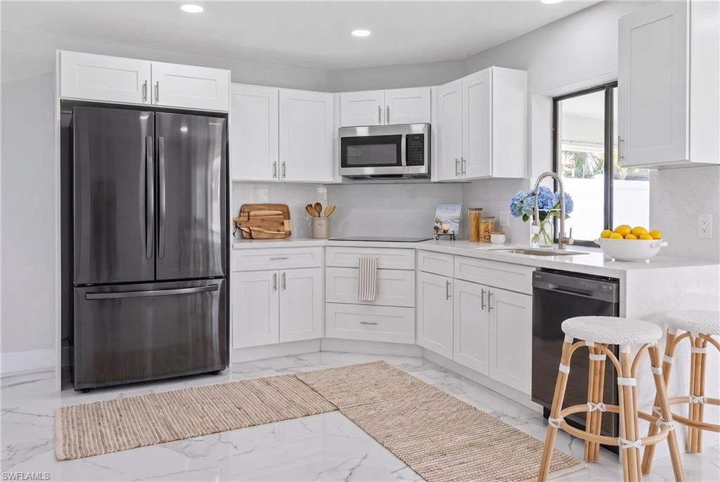 White shaker cabinetry, stainless steel appliances, and light countertops define this kitchen space