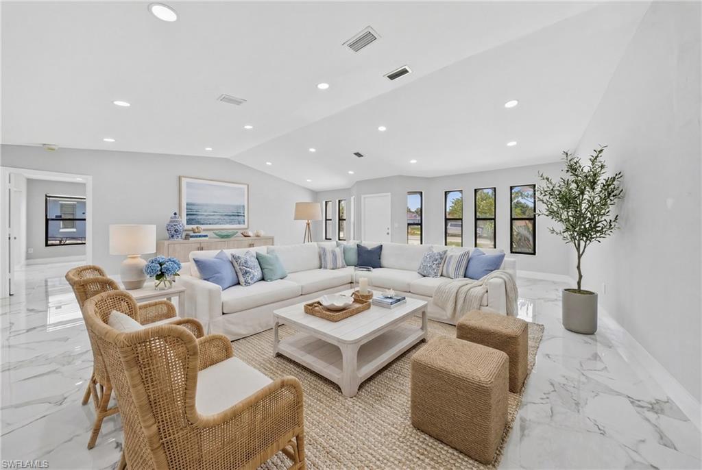 Spacious living area featuring white marble-look flooring, multiple recessed lights, and several windows with dark trim