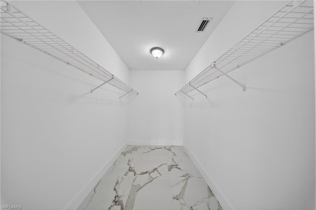 Walk-in closet featuring white wire shelving on opposing walls, white baseboards, and a contemporary flush-mount ceiling light