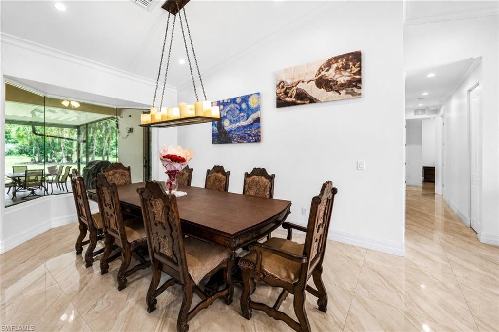 Spacious interior room featuring light-toned tile flooring, vaulted ceilings with crown molding, and a large bay window with screened enclosure access