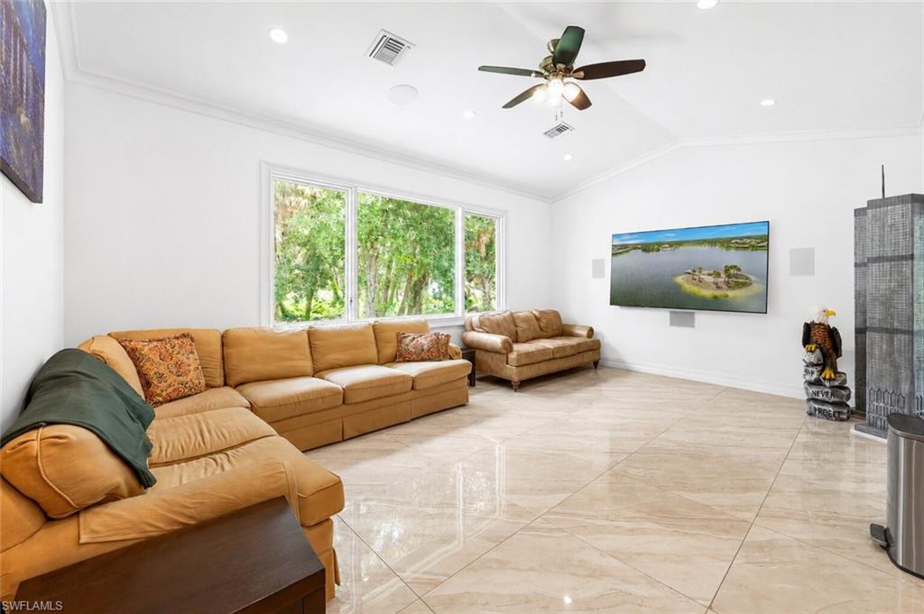 Spacious living area featuring large format tile flooring, a vaulted ceiling, and recessed lighting