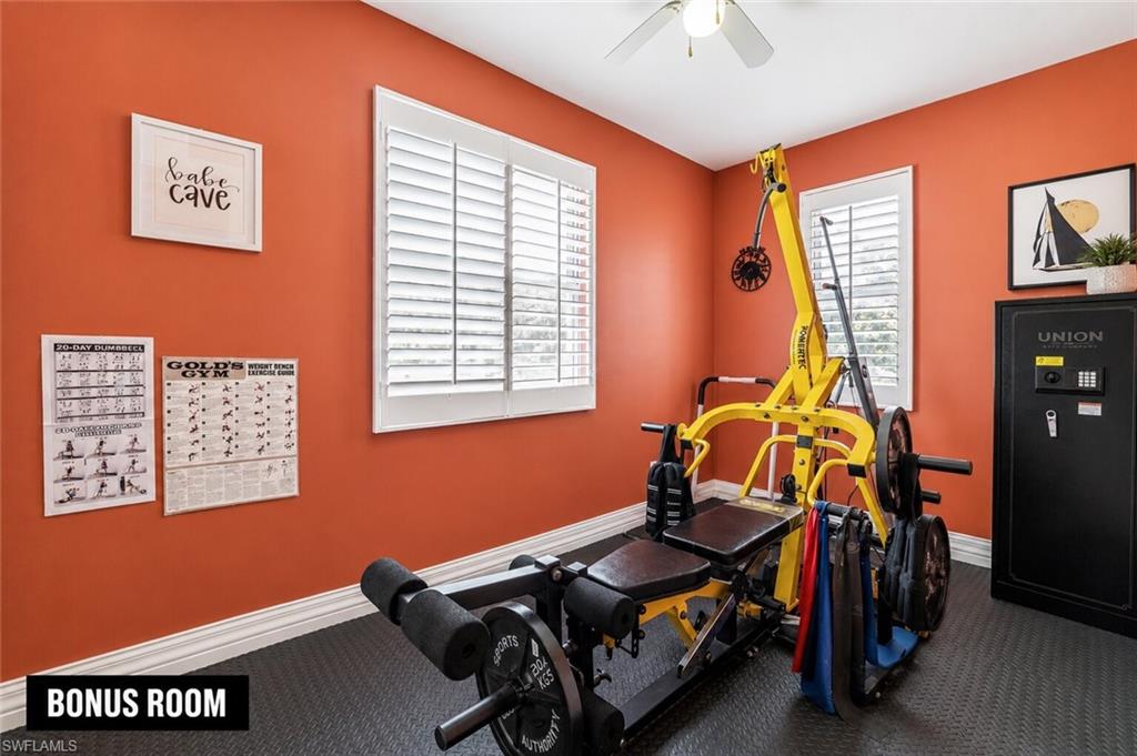 Dedicated bonus room featuring solid orange walls, white window shutters, a ceiling fan, and textured dark flooring