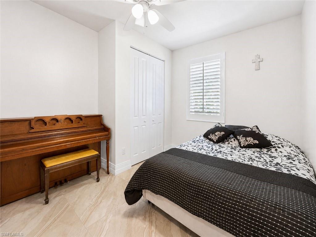 Bright bedroom featuring light-toned tile flooring, white walls, and a ceiling fan
