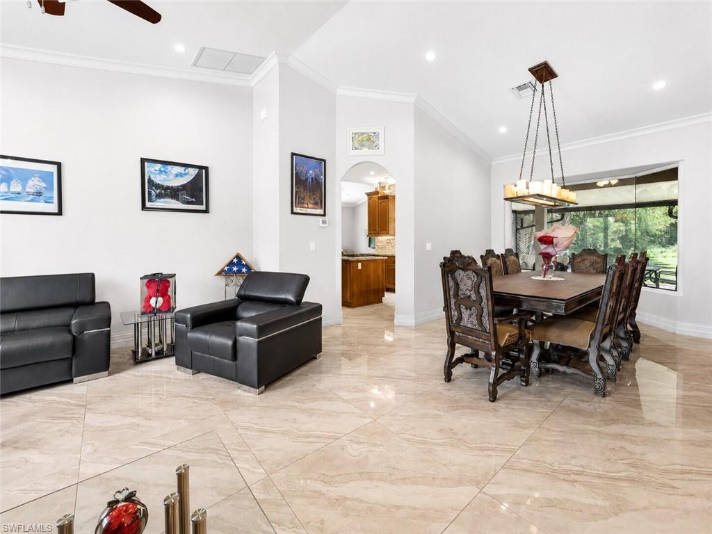 Spacious living area featuring large format tile flooring, crown molding, recessed lighting, and a decorative chandelier