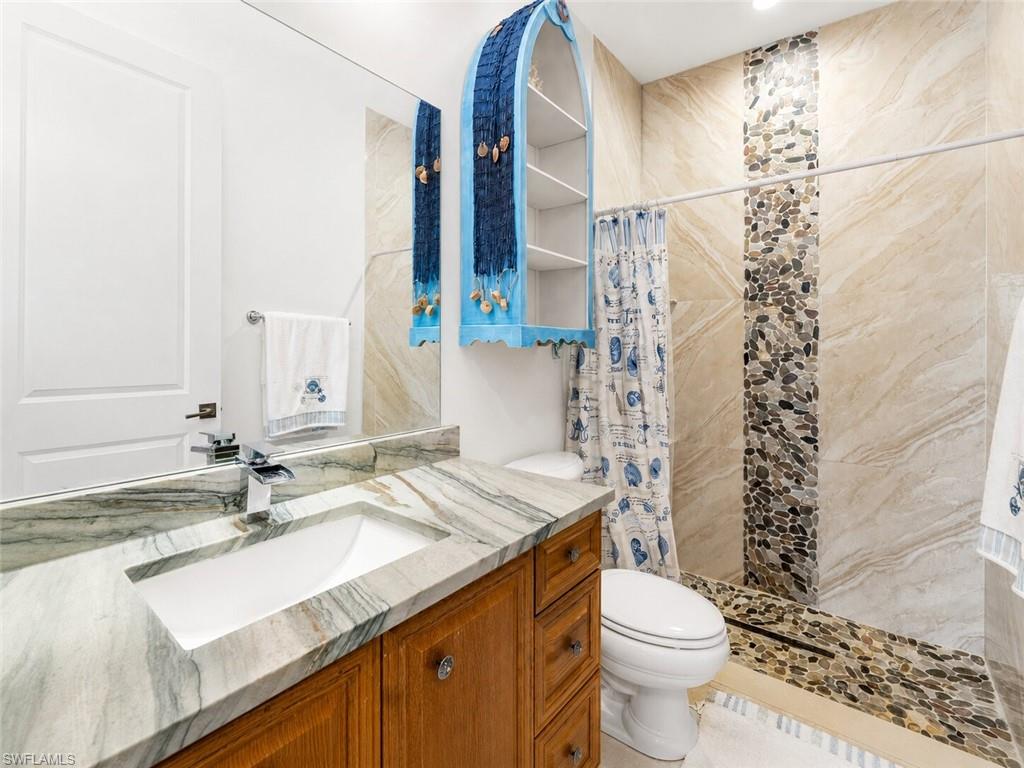 Bathroom featuring a wood vanity with a built-in sink and a patterned stone countertop