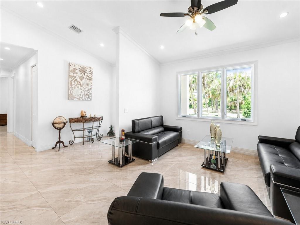 Living area featuring large format tile flooring, crown molding, recessed lighting, and a ceiling fan