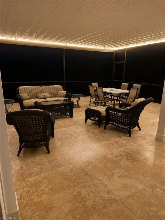 Expansive covered patio featuring a paneled ceiling with integrated lighting, durable tile flooring, and dark-framed screens