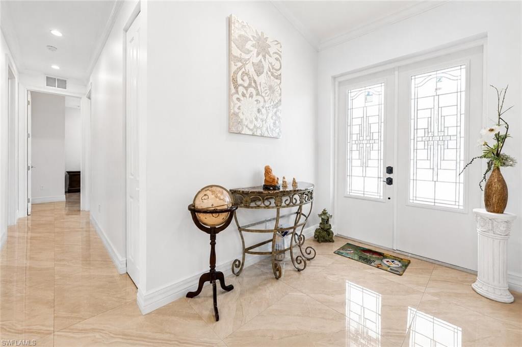 Entryway featuring double doors with decorative glass panels, light-toned polished tile flooring, recessed ceiling lighting, and crown molding