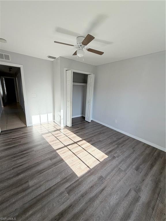 Spacious room featuring wood-finish flooring, light gray wall paint, and a ceiling fan with wood-tone blades