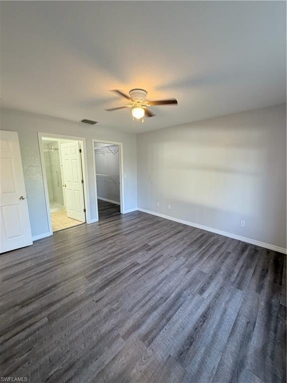 Spacious room featuring wood-finish flooring, a ceiling fan with integrated lighting, white baseboards, and neutral wall tones
