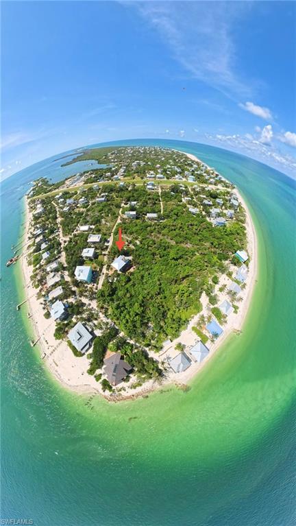 Coastal land parcel on a barrier island, featuring surrounding clear blue-green waters, white sand beaches, and lush natural vegetation