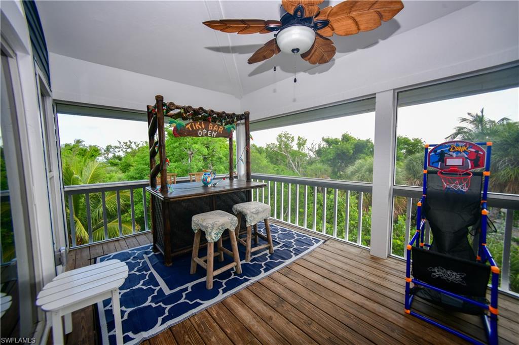 Screened porch with wood-finish flooring, a ceiling fan with leaf-shaped blades, and a white railing system
