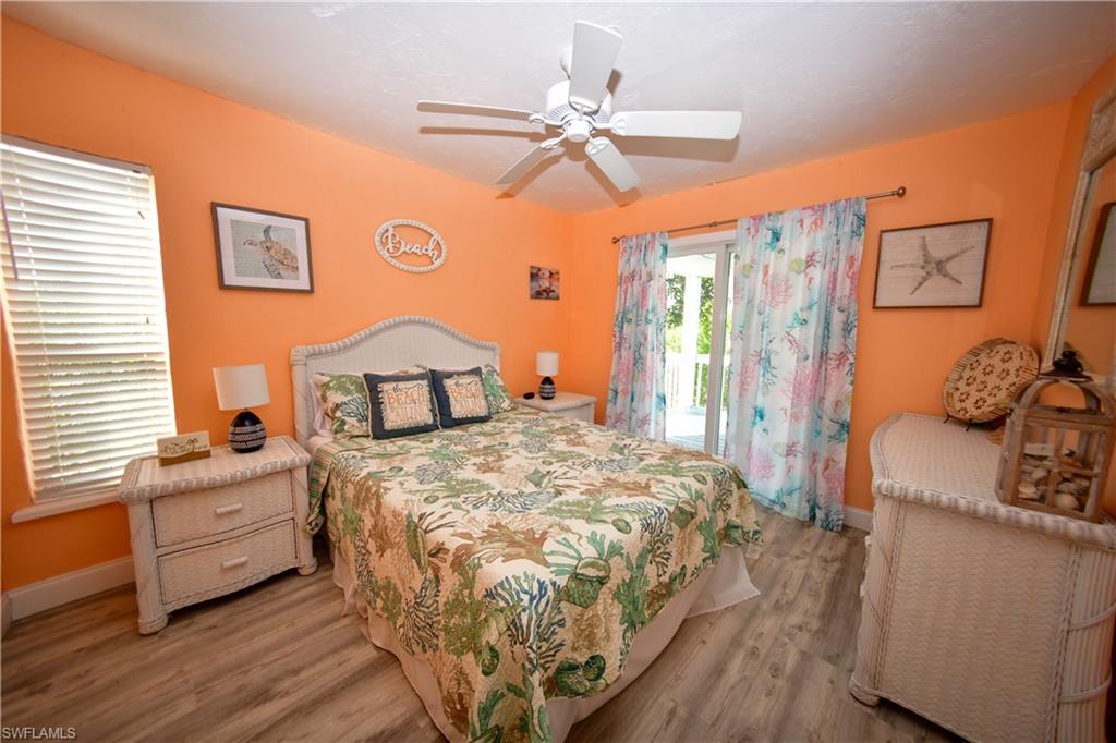 Bedroom featuring a ceiling fan, wood-finish flooring, a window with blinds, and white patio doors