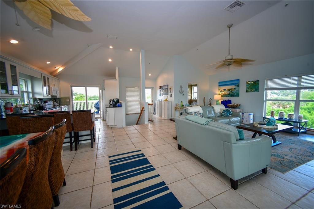 Open-concept living space featuring vaulted ceilings, recessed lighting, and tile flooring