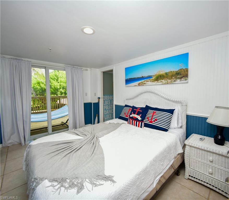 Bedroom featuring tile flooring, white beadboard wall paneling, recessed lighting, and sliding glass doors leading to an outdoor deck