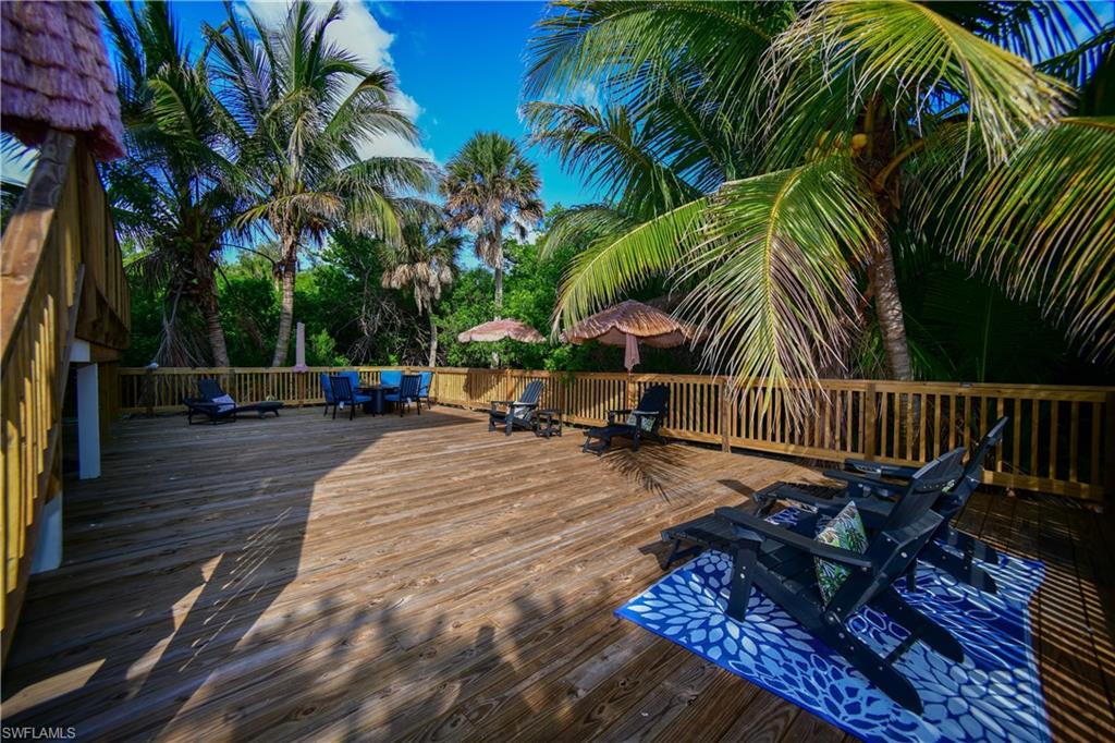 Expansive wood deck with a slatted wood railing, surrounded by mature palm trees and lush foliage