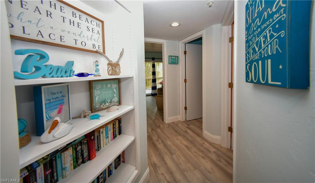 Hallway featuring built-in shelving, wood-finish flooring, recessed lighting, and light-colored walls