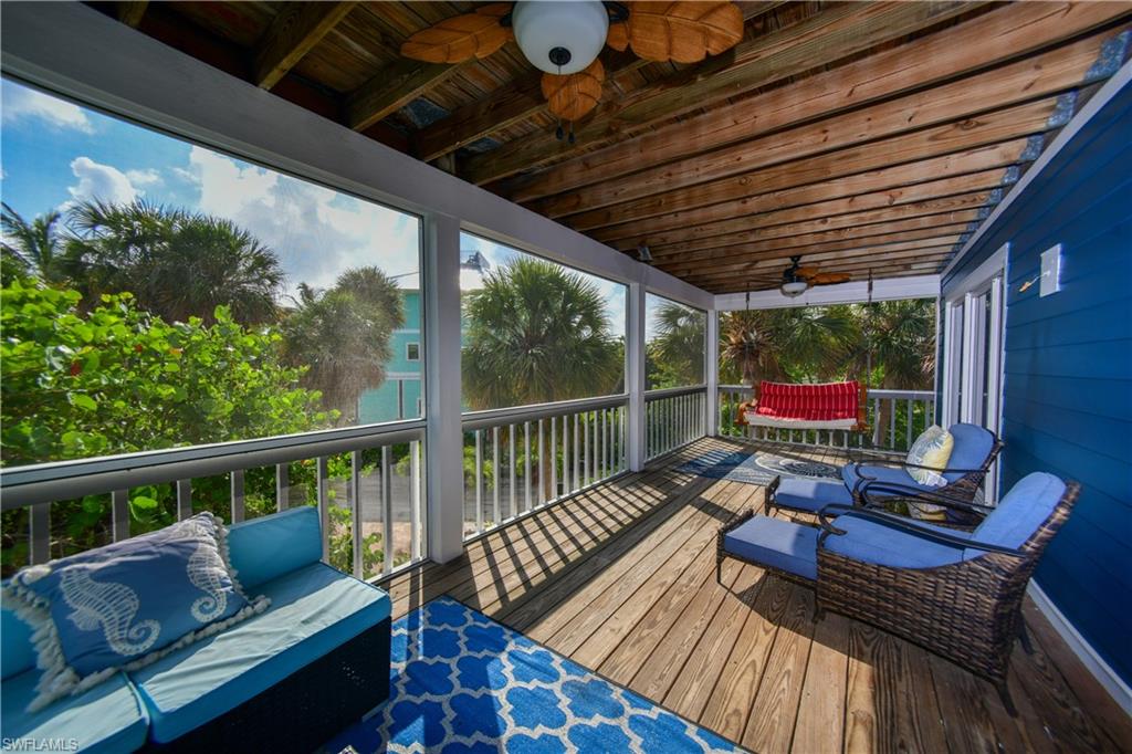 Spacious screened-in porch with wood flooring and exposed wood ceiling beams