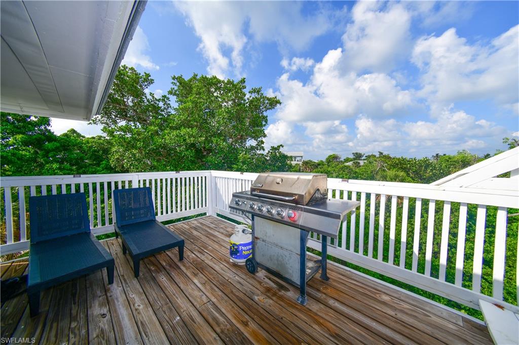 Upper-level wood deck featuring white railing and abundant natural foliage