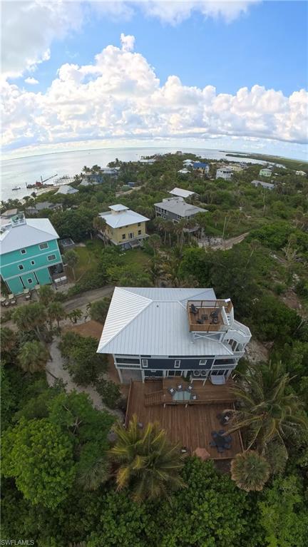 Coastal property featuring a spacious wood deck, metal roof, and an elevated rooftop deck