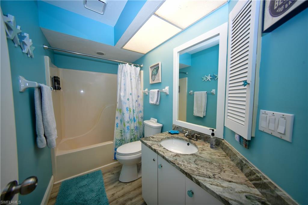 Bathroom featuring a vanity with an integrated sink, stone countertop, wood-finish flooring, and a shower-tub combination
