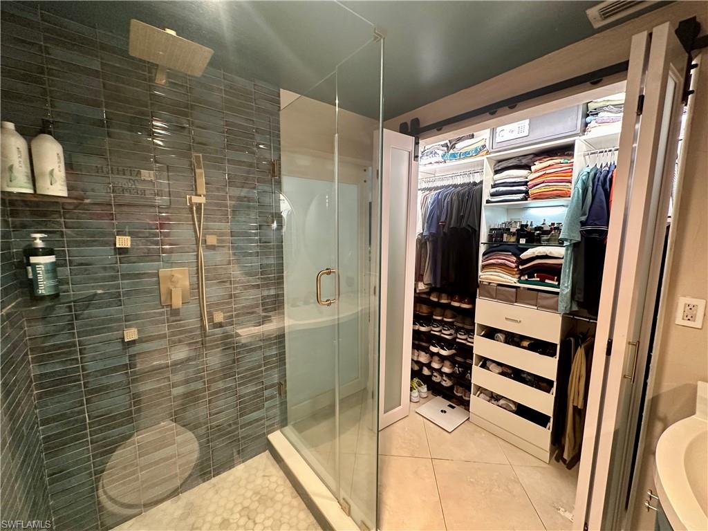 Walk-in shower with full glass enclosure, rain showerhead, handheld shower, and rectangular wall-mounted shower fixtures