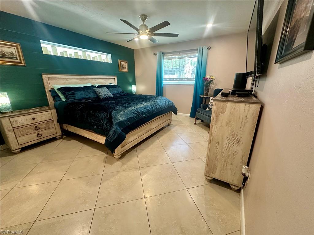 Spacious bedroom featuring tile flooring, a horizontal recessed wall niche, and a ceiling fan with integrated lighting