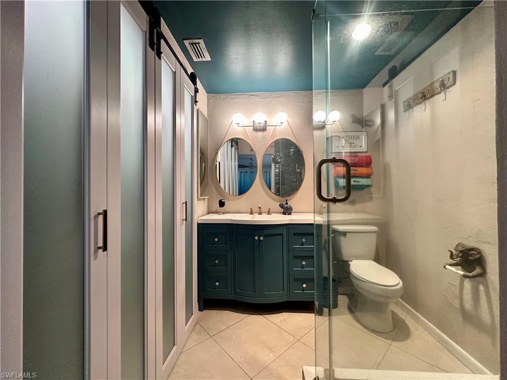 Bathroom featuring a dual vanity with a teal base cabinet, double oval mirrors, and a glass-enclosed shower with a bronze handle