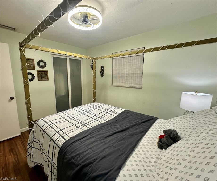 Bedroom featuring wood-finish flooring, light green walls, a ceiling-mounted light fixture, and a white interior door