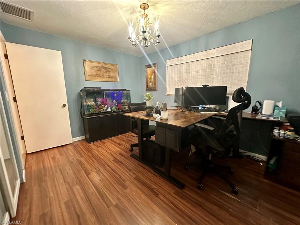 Interior space featuring wood-finish flooring, light blue wall paint, and a decorative chandelier light fixture