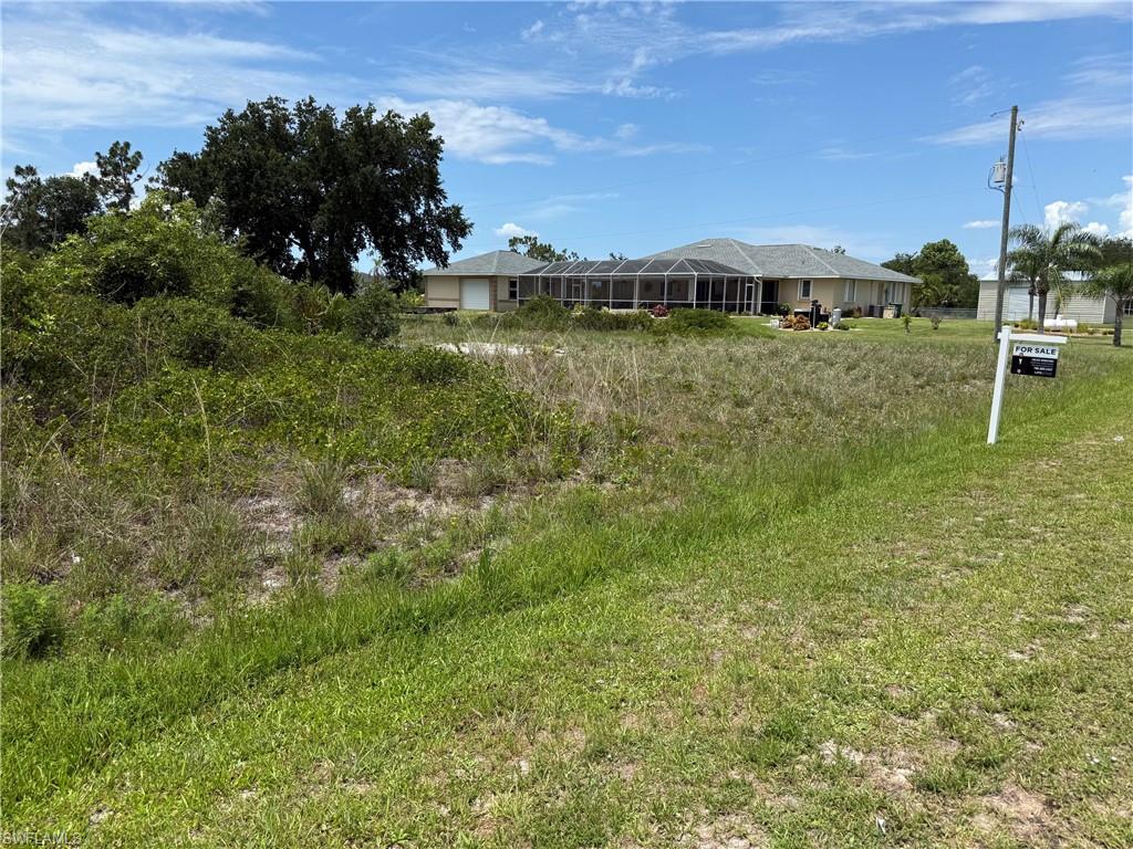 Generous parcel of land featuring natural ground cover, mature trees, and a clear sky