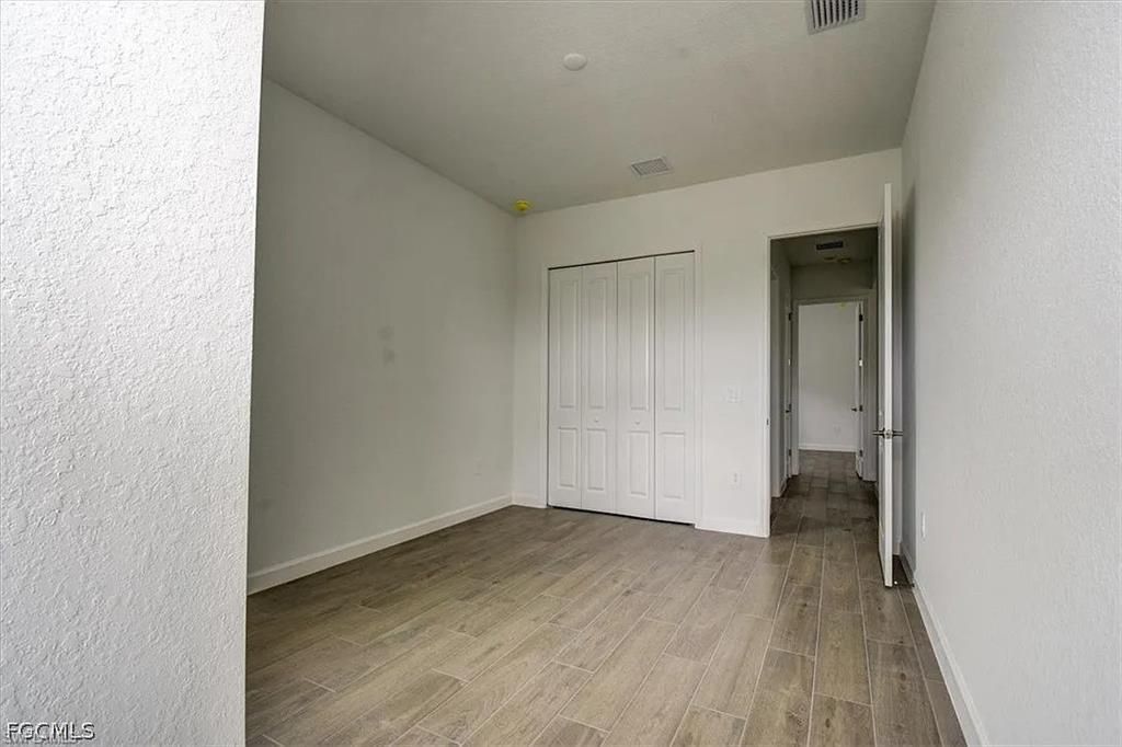Room featuring wood-finish tile flooring, a bi-fold door closet, and white painted walls